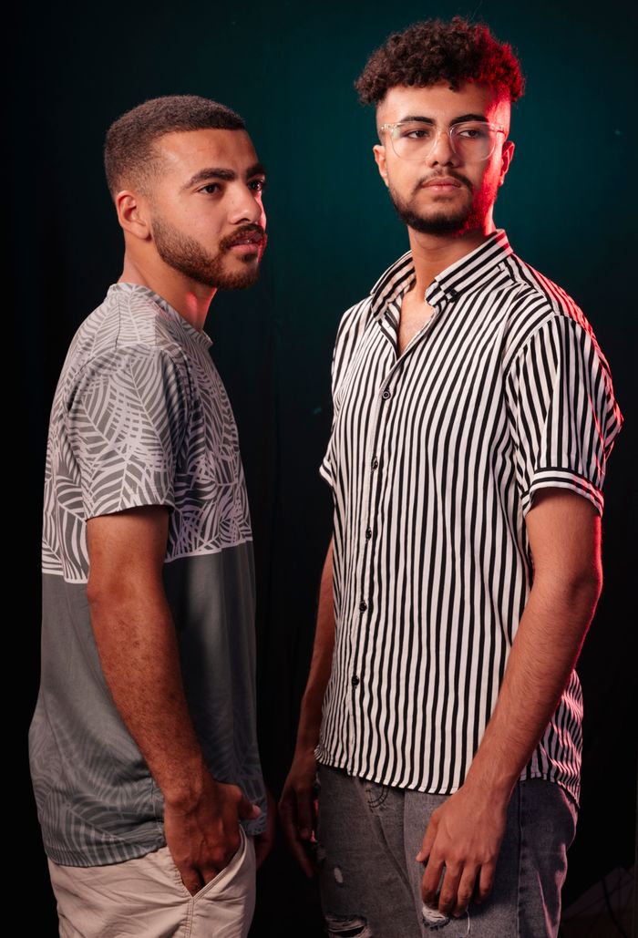 Studio portrait of two young men in stylish outfits, showcasing modern casual fashion.
