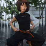 Young adult in cowboy hat posing creatively outdoors with bold fashion style.
