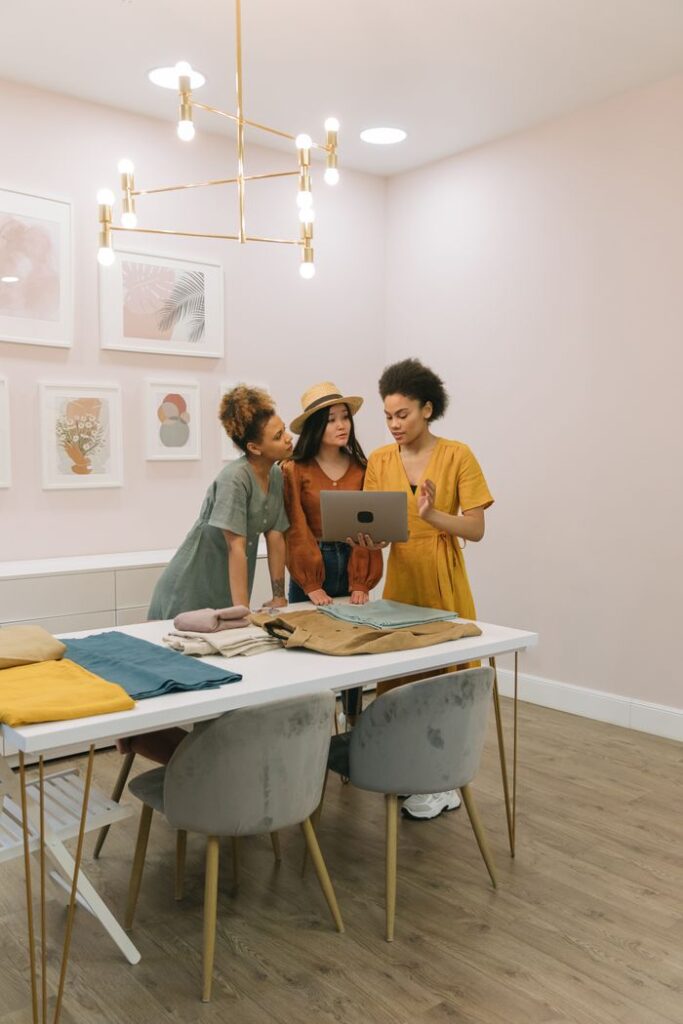Three women fashion designers collaborating on a project using a laptop in a stylish room.